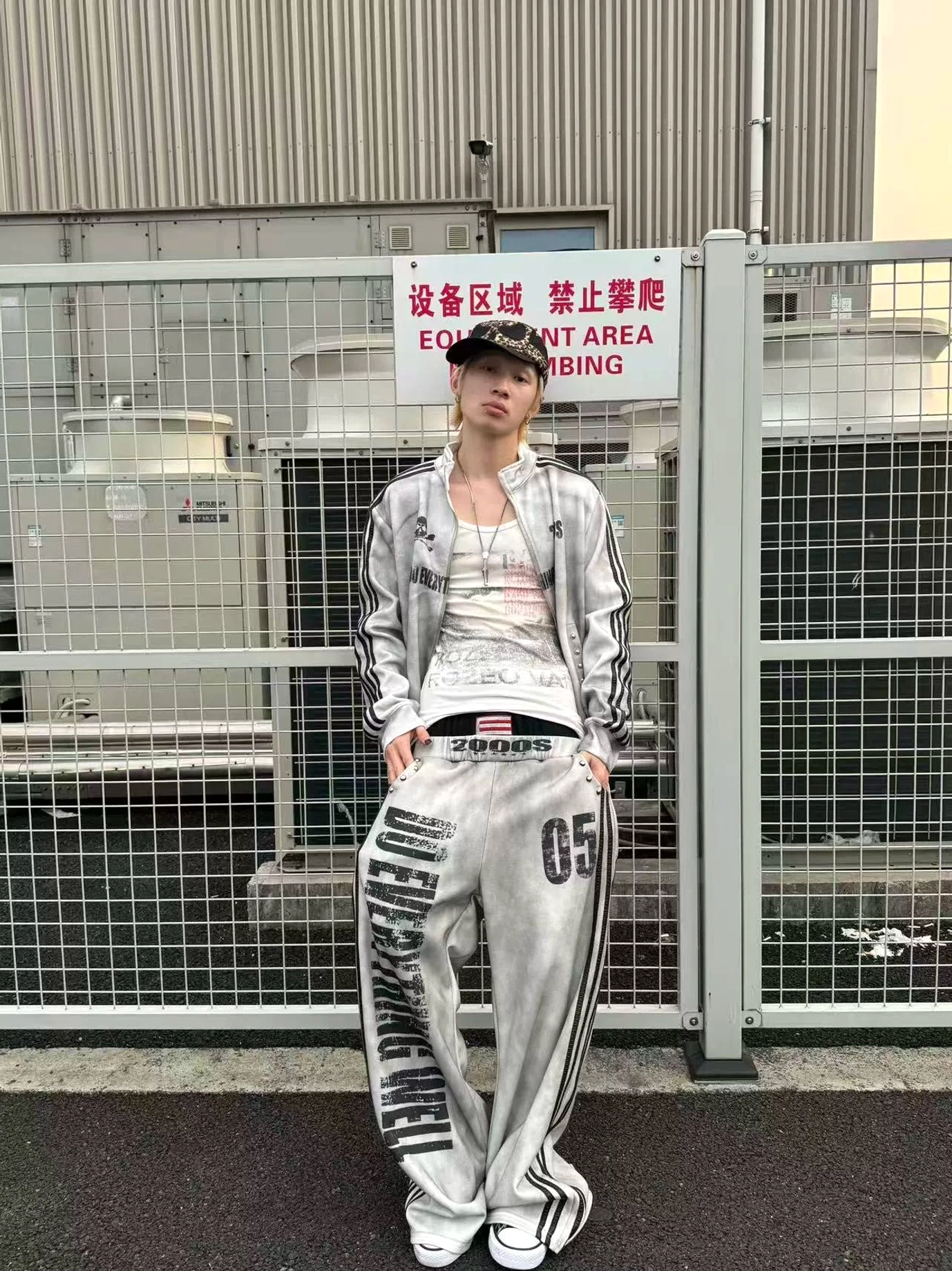 Front view of a Y2K washed track jacket styled open over a white tank top with matching wide-leg pants and sneakers