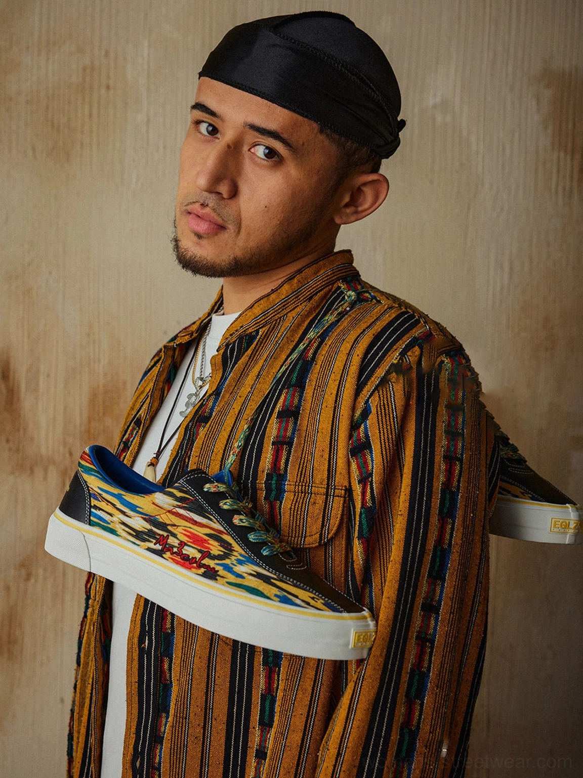 Model holding matching yellow abstract print canvas skate shoes with colorful streetwear artwork