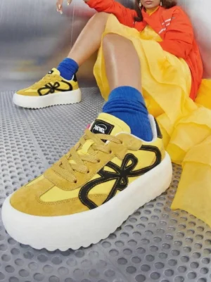 Yellow and black chunky platform sneakers styled with blue crew socks in a colorful streetwear outfit