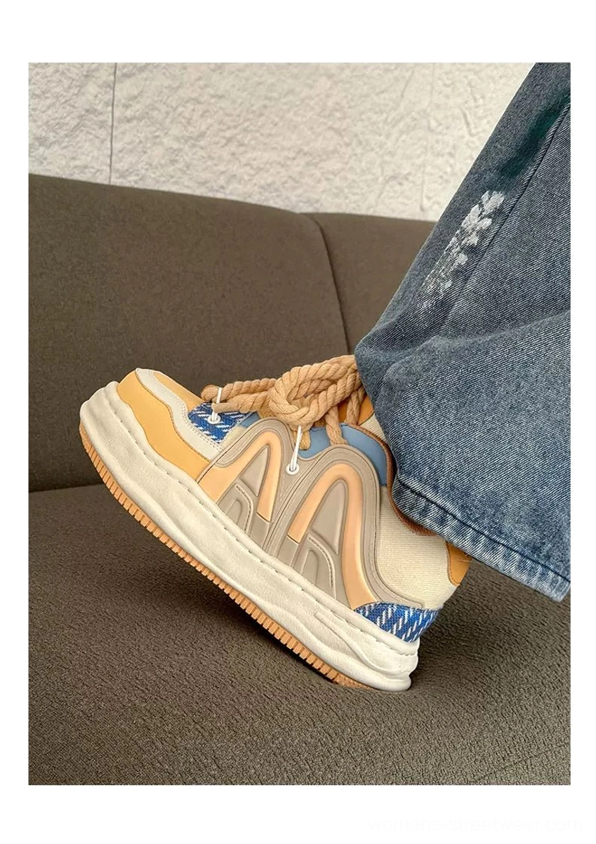 Yellow-brown and blue color-block platform sneakers worn with washed denim jeans, featuring thick rope laces and a bold chunky streetwear profile