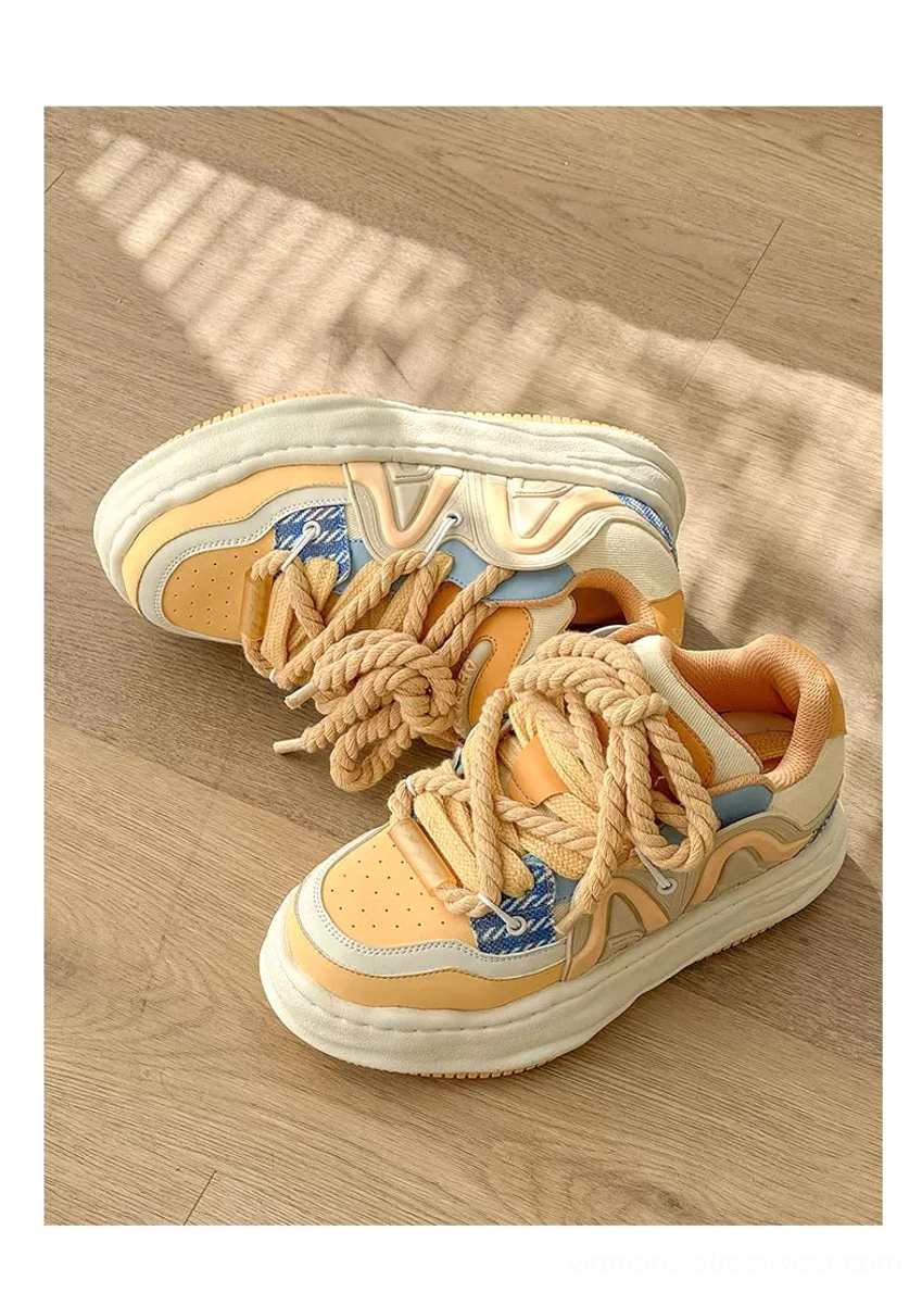 Yellow-brown chunky rope lace platform sneakers displayed on a wooden floor with color-blocked panels, thick sole, and contemporary streetwear styling
