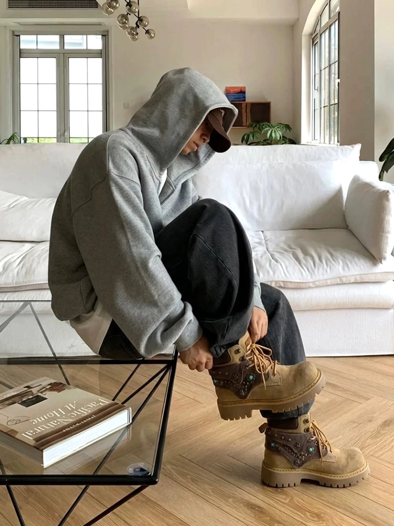 Rear three-quarter view of yellow-brown embellished western ankle boots with chunky lug outsole and casual black trousers
