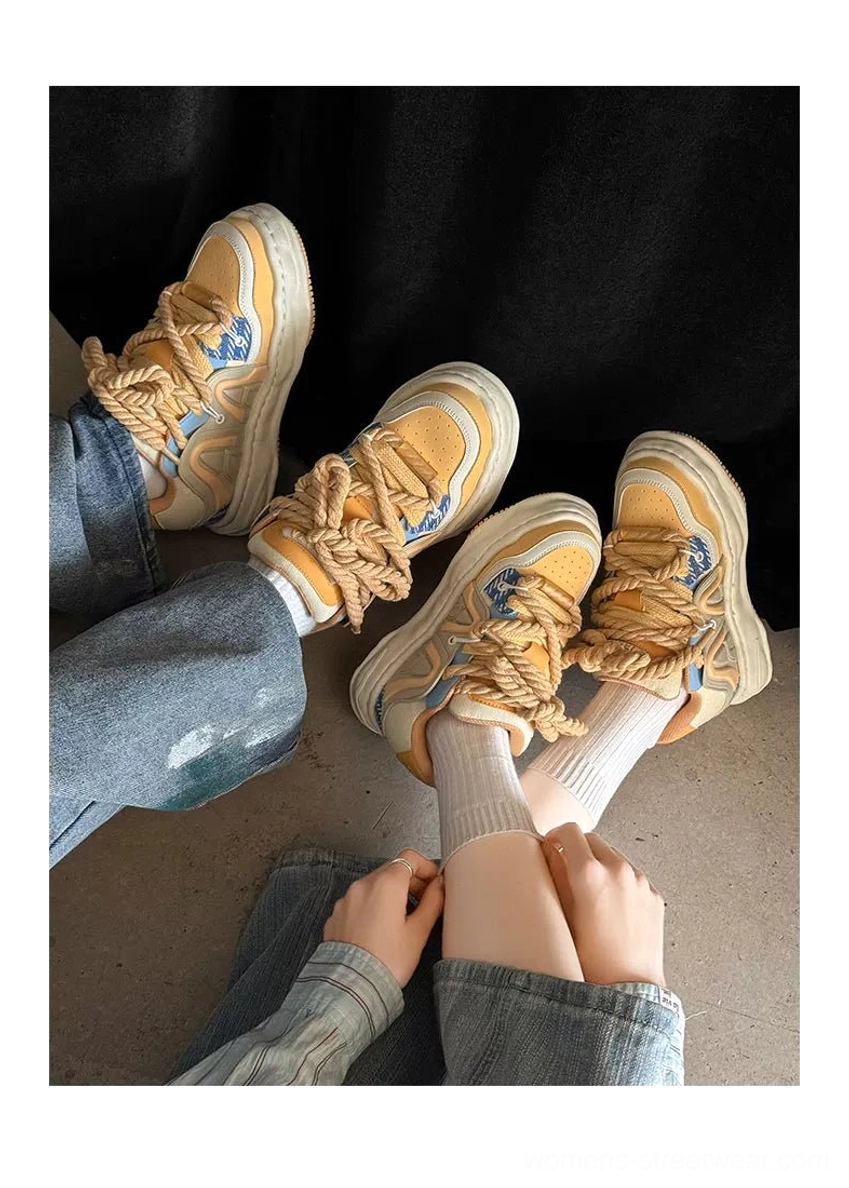 Yellow-brown chunky rope lace platform sneakers worn with blue jeans and white socks, highlighting the oversized laces and thick urban streetwear sole