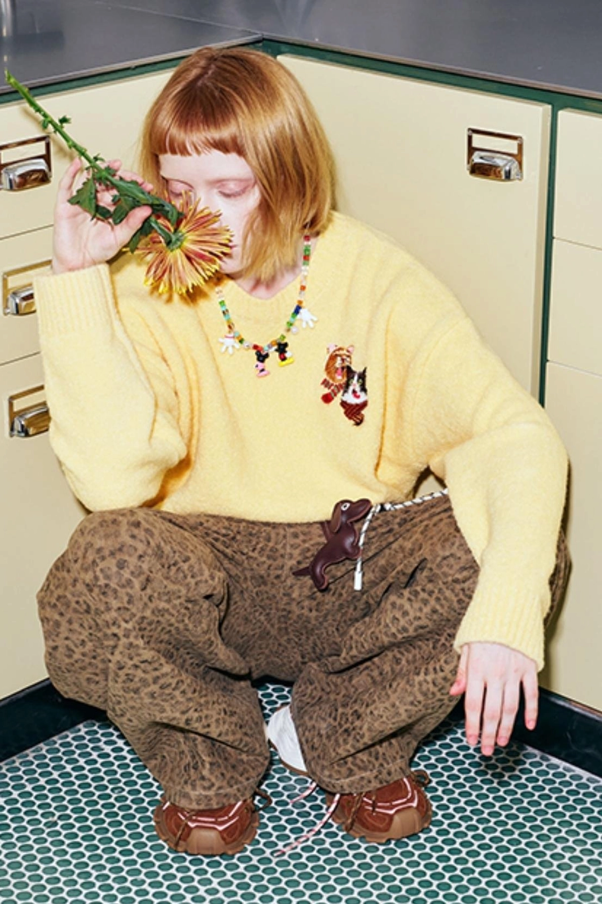 Close three-quarter view of yellow cat embroidered knit sweater highlighting sleeve length and fuzzy textured fabric