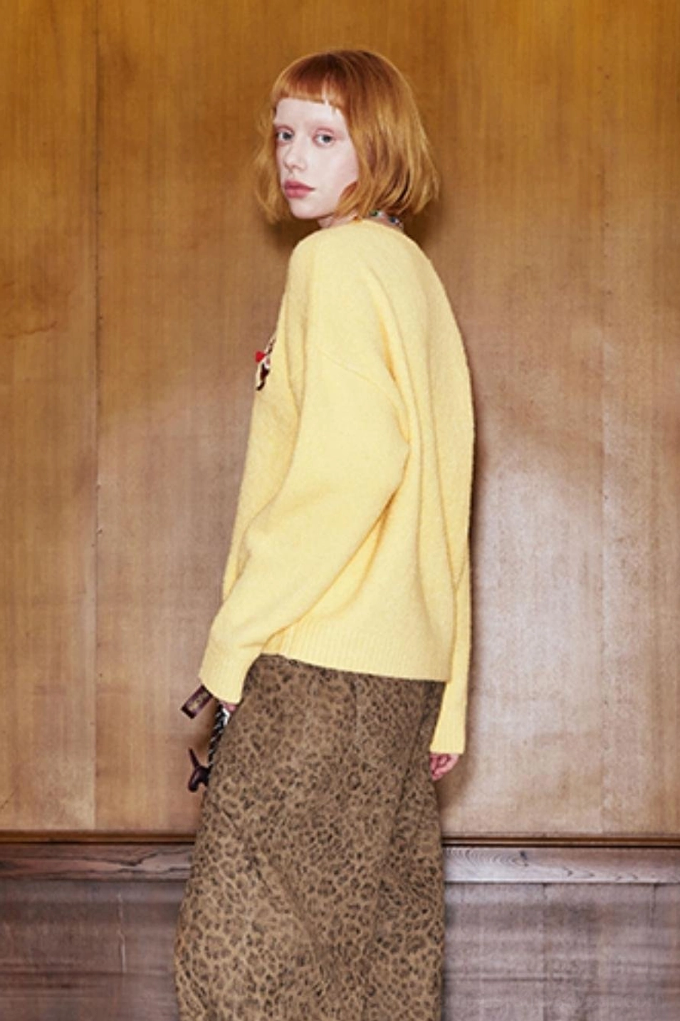 Side view of relaxed yellow cat knit sweater showing long loose sleeves and soft textured knit fabric
