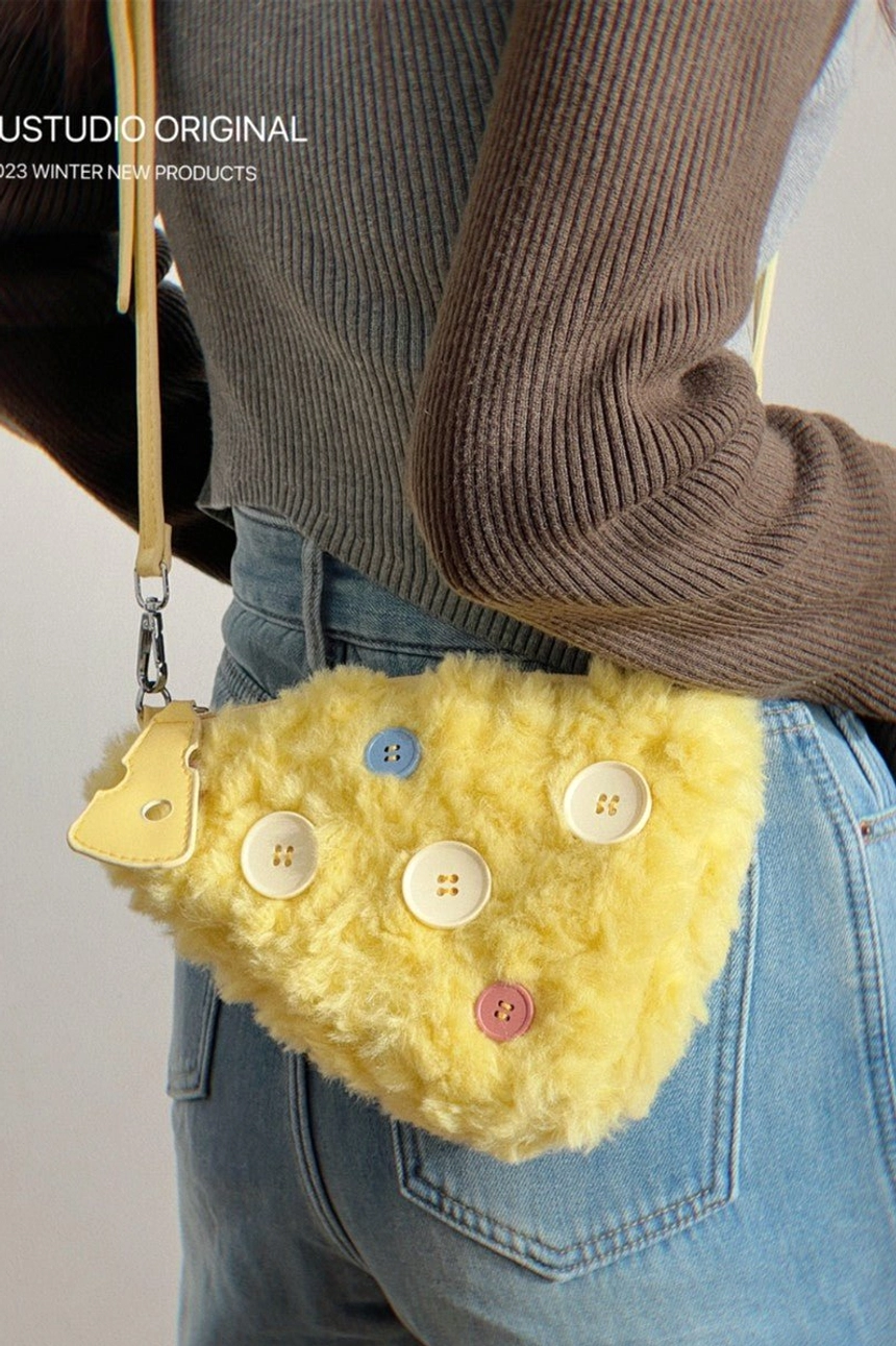 Front view of yellow cheese fuzzy mini shoulder bag worn at the waist with multicolor buttons metal hardware and strap