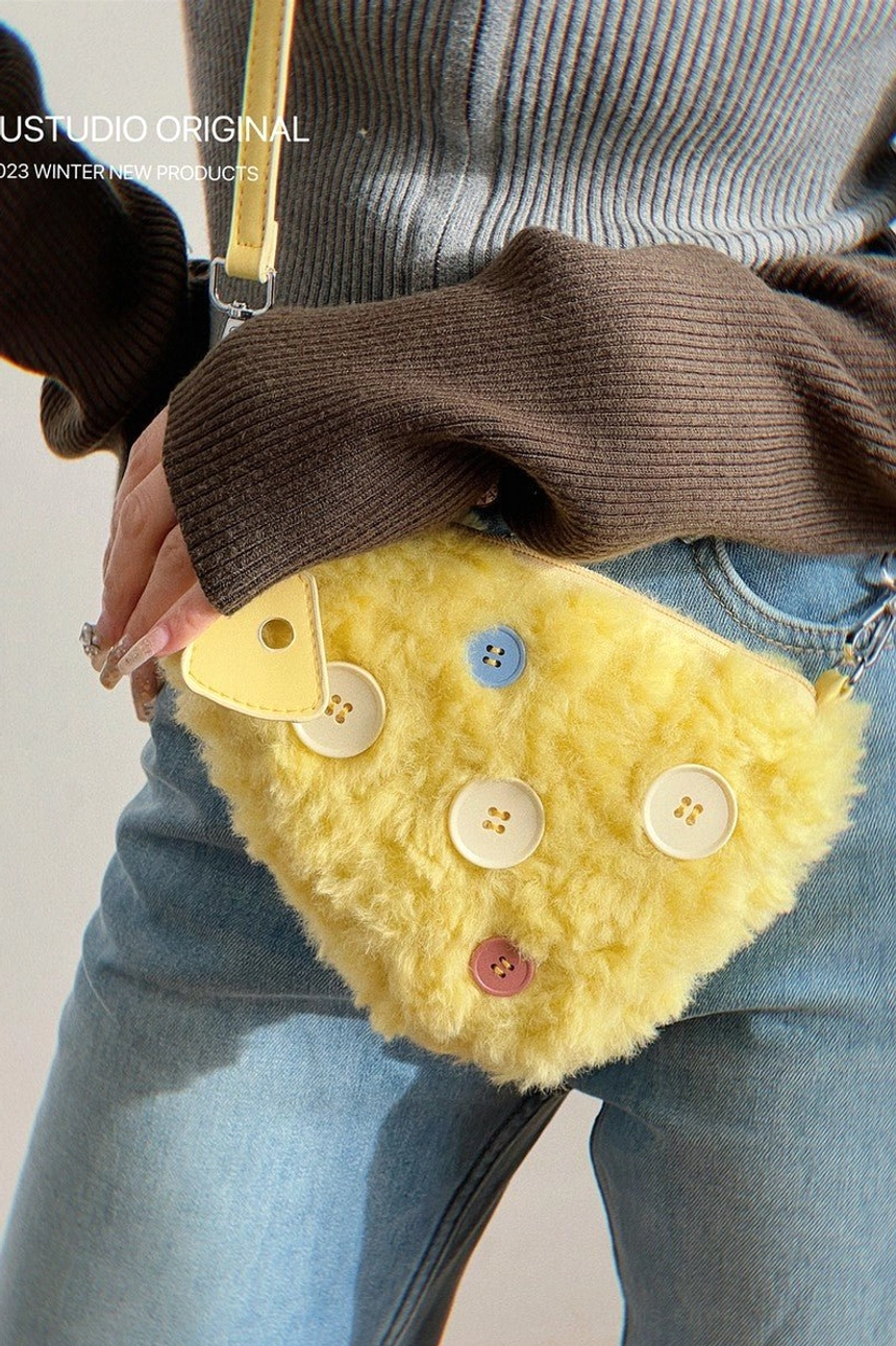 Side close-up of yellow fuzzy cheese crossbody bag with pink blue and white button decorations and matching strap