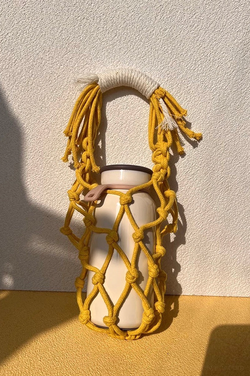 Yellow cotton macrame water bottle carrier featuring a colorful hand-knotted net design and lightweight everyday handle