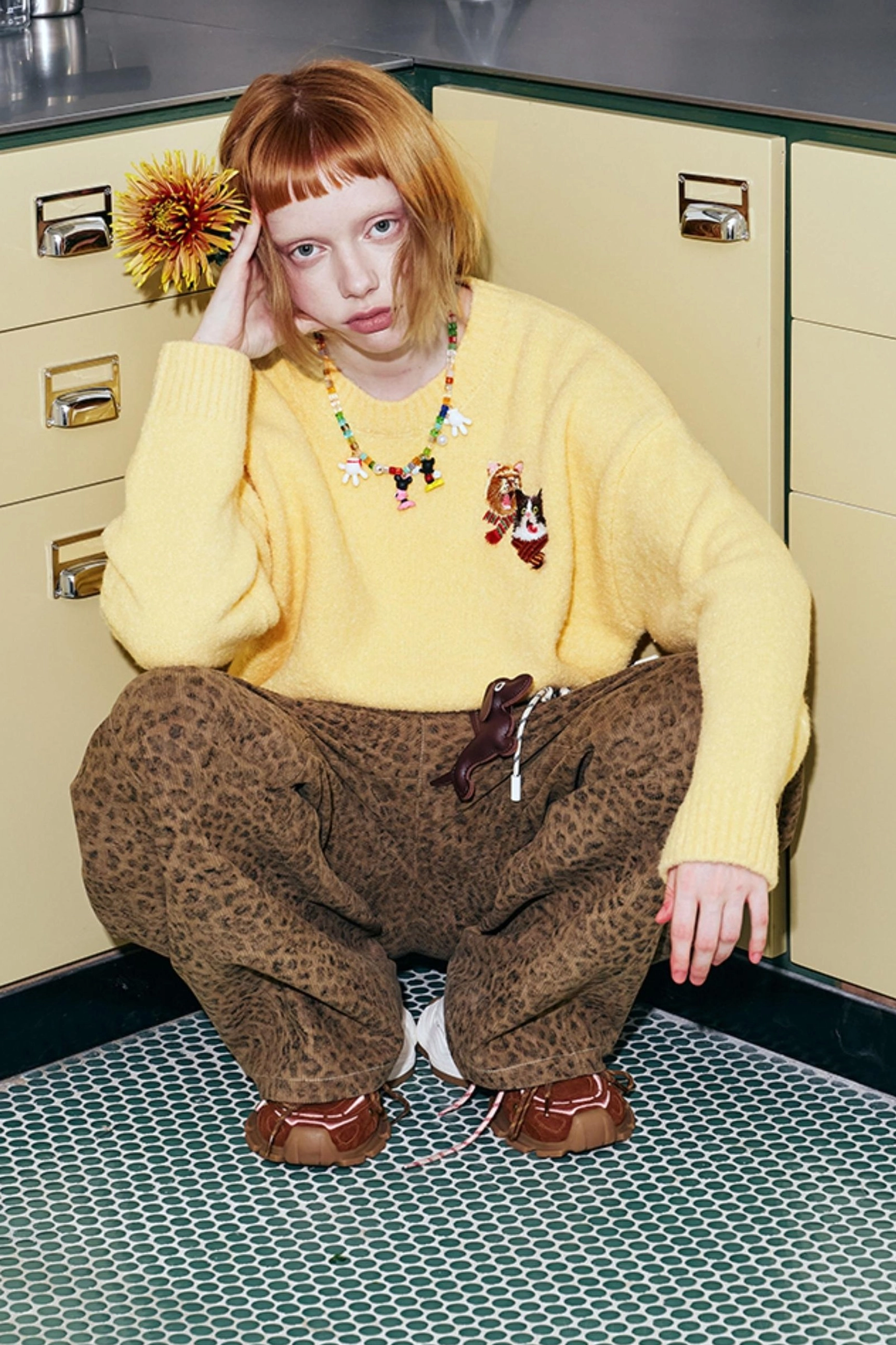 Yellow embroidered cat sweater styled with leopard print pants and vintage accessories in a retro casual outfit