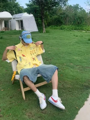 Yellow embroidered floral short sleeve shirt with colorful botanical artwork and graphic text in a relaxed summer streetwear look