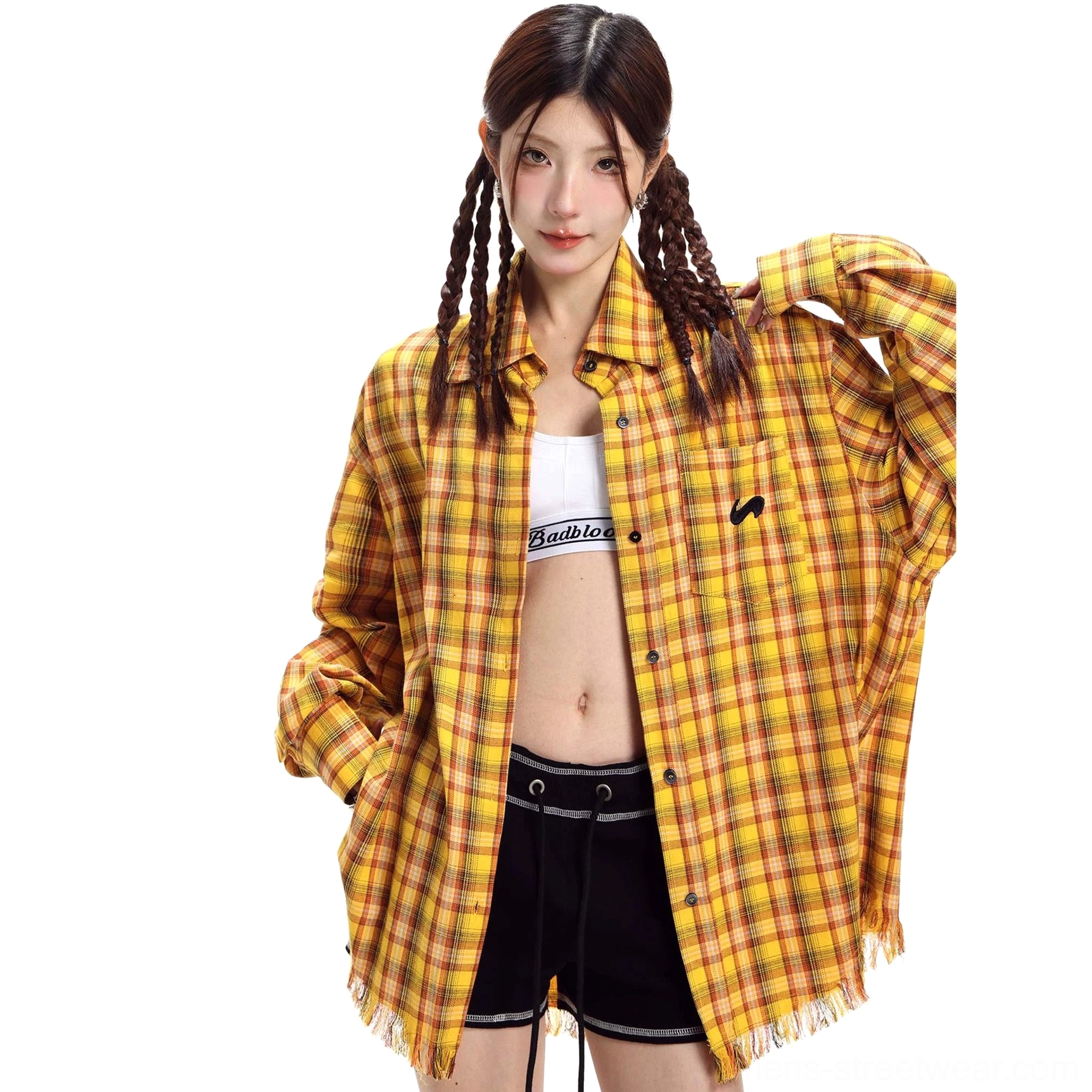 Yellow plaid oversized streetwear shirt with frayed hem shown from the front side on a model wearing a crop top and black shorts