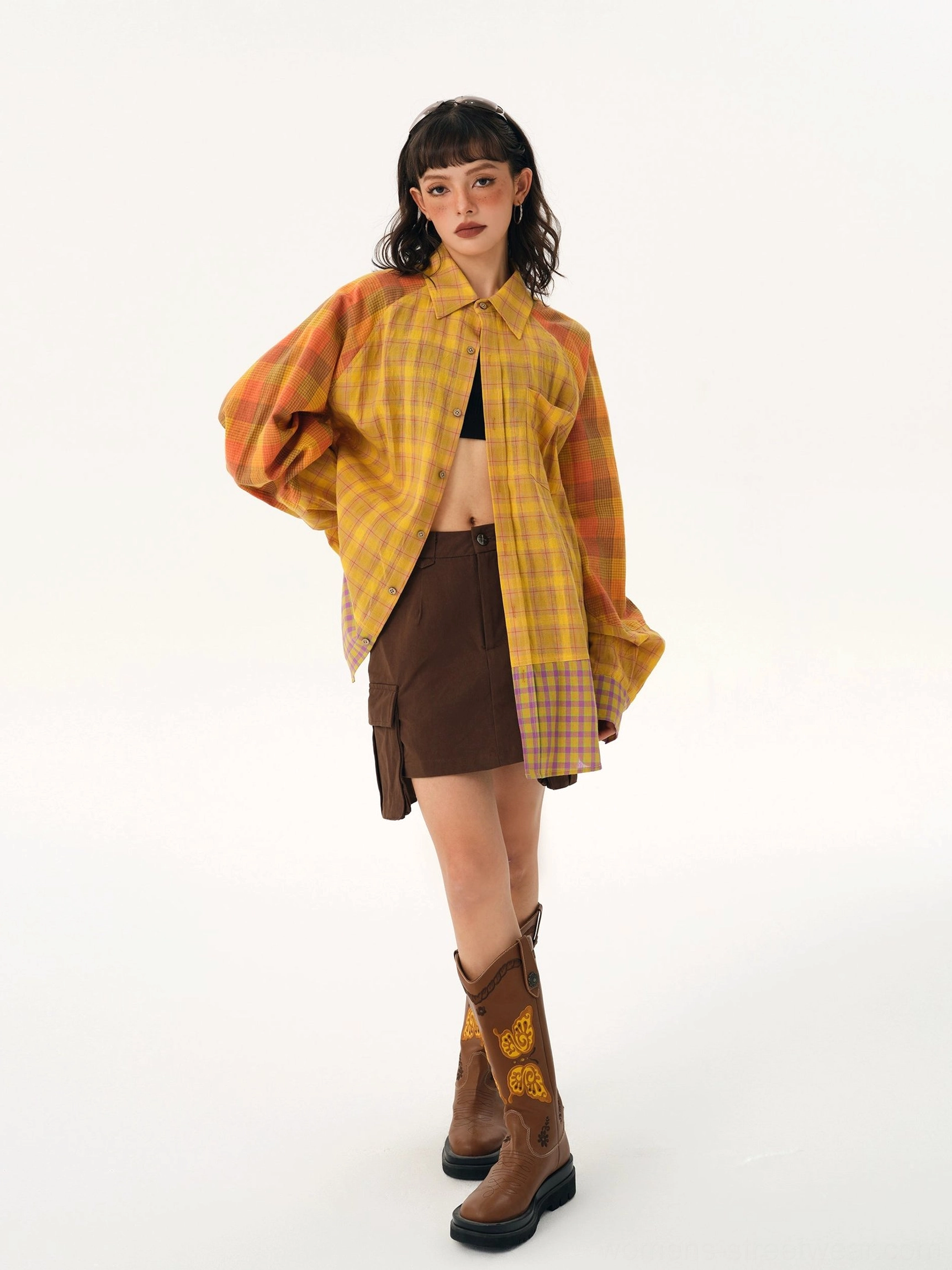 Yellow plaid patchwork oversized shirt front view worn as an open streetwear layer with black crop top and brown mini skirt