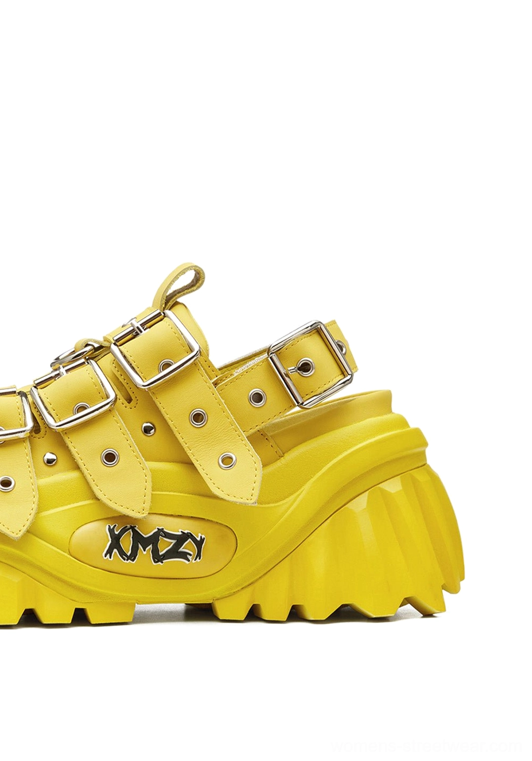 Three-quarter side close-up of yellow punk platform sandals with silver buckles and serrated chunky outsole