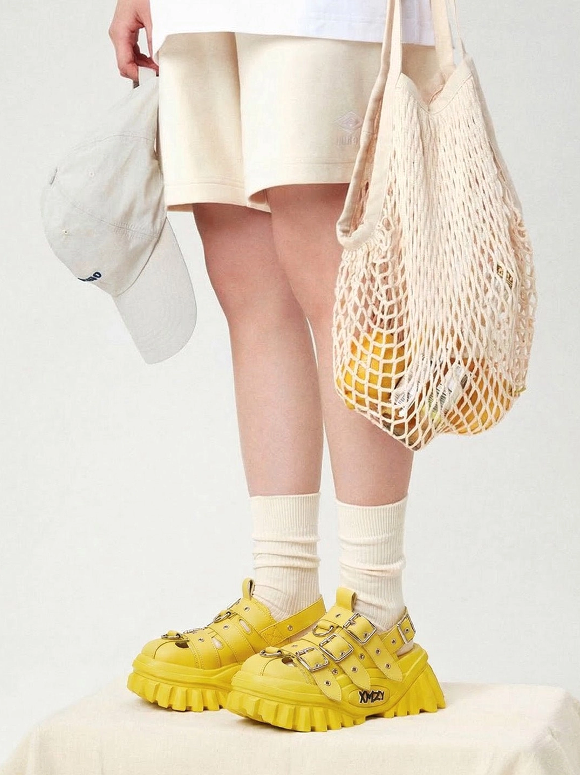 Yellow triple-buckle platform sandals worn with a relaxed casual streetwear outfit and mesh tote bag