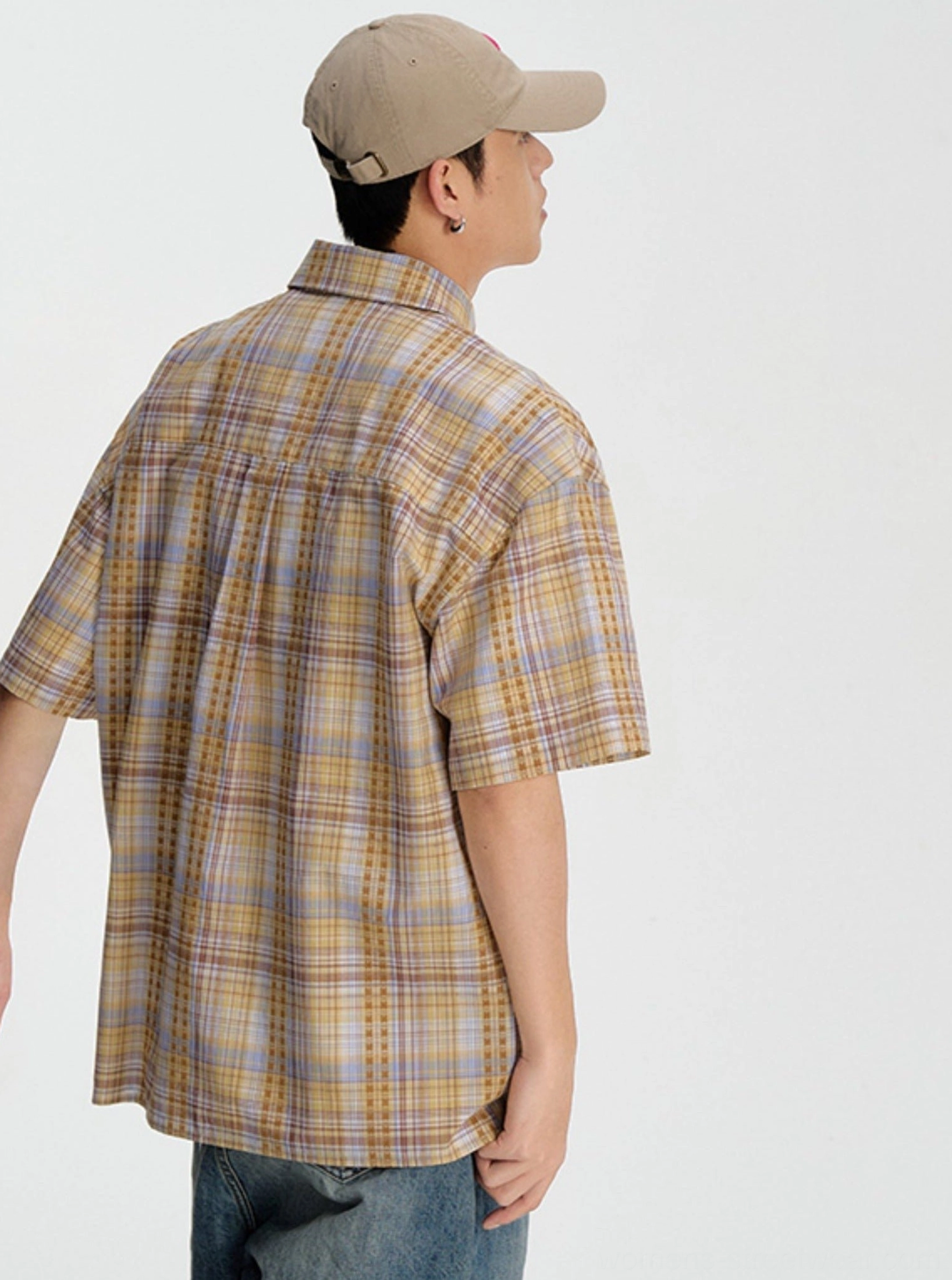 Back view of a yellow and purple plaid short sleeve streetwear shirt showing its relaxed loose silhouette and checkered pattern