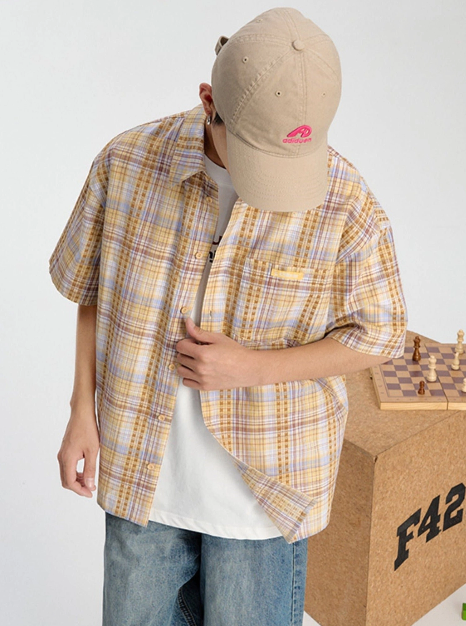 Yellow and purple plaid short sleeve shirt shown from a front three-quarter angle with chest embroidery and relaxed Korean streetwear styling
