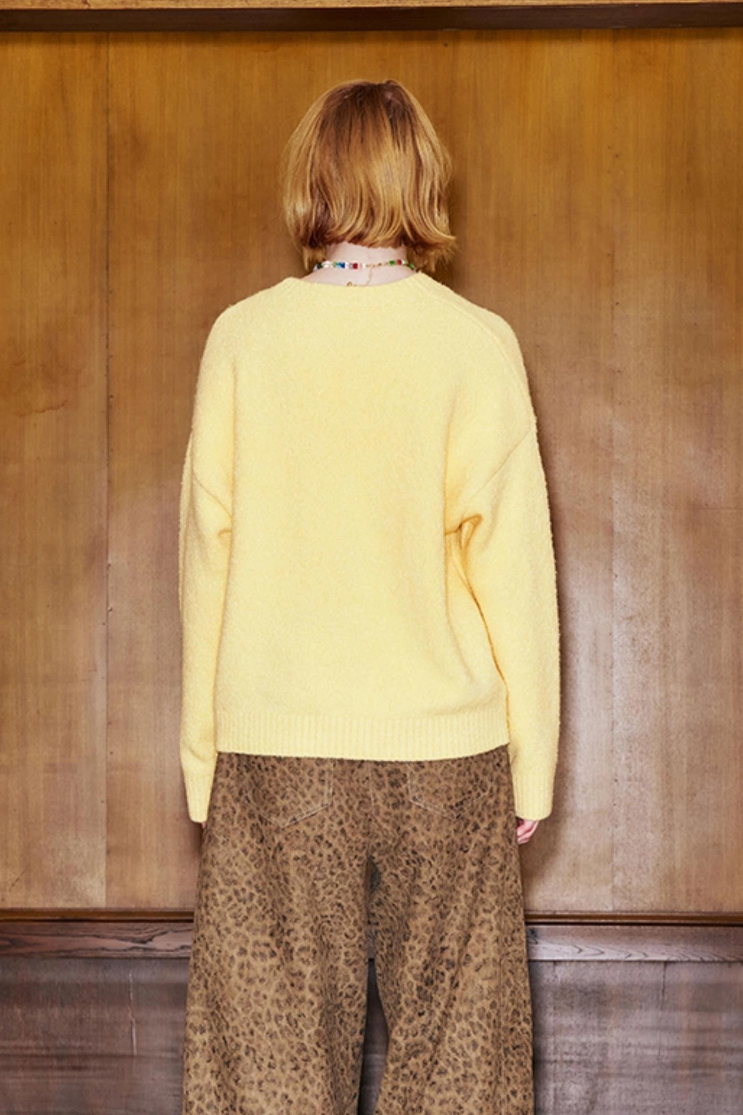 Back view of yellow relaxed crewneck knit sweater with clean minimalist solid back design
