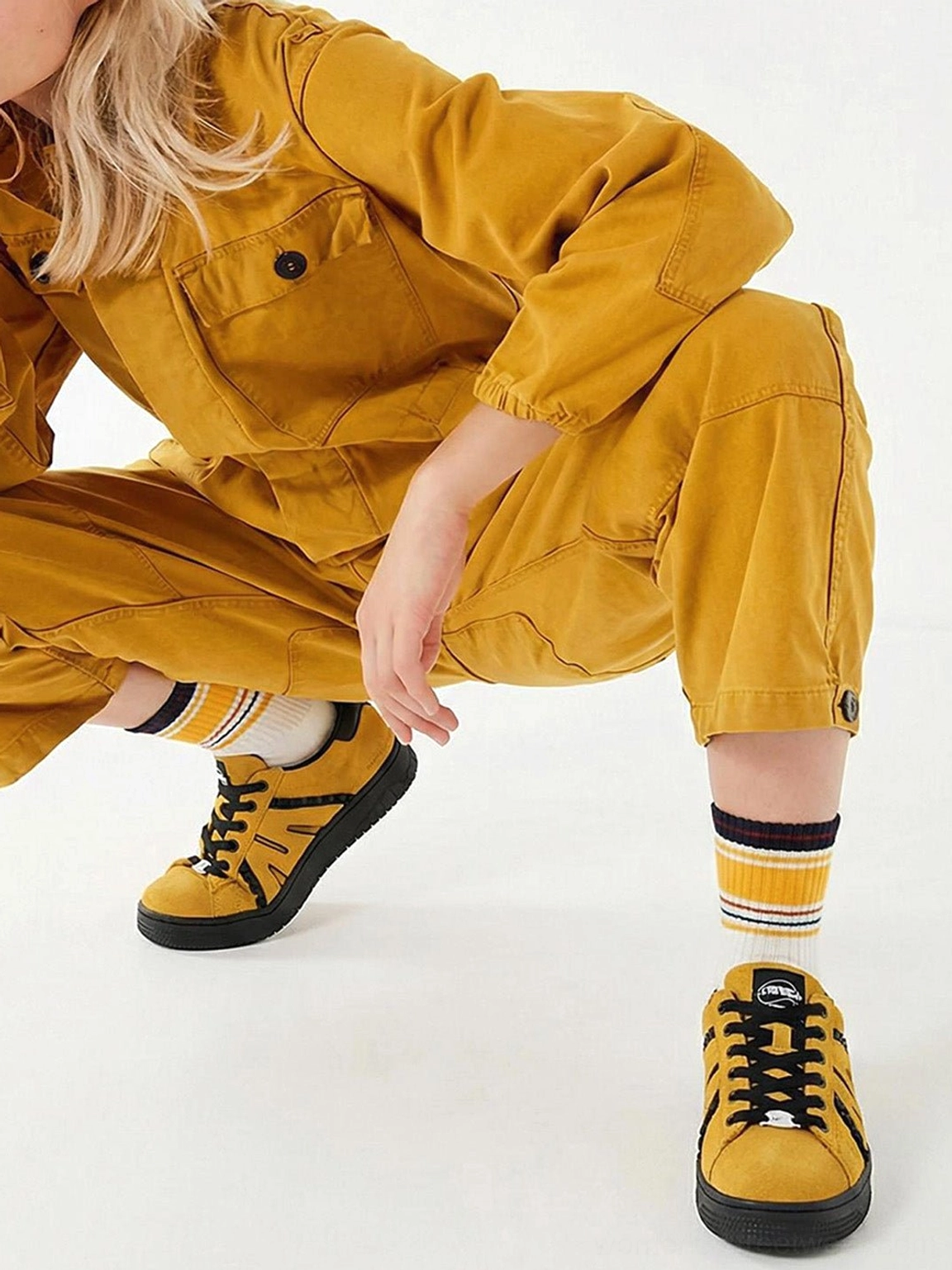 Mustard yellow suede platform sneakers styled with yellow workwear, striped socks, and black laces
