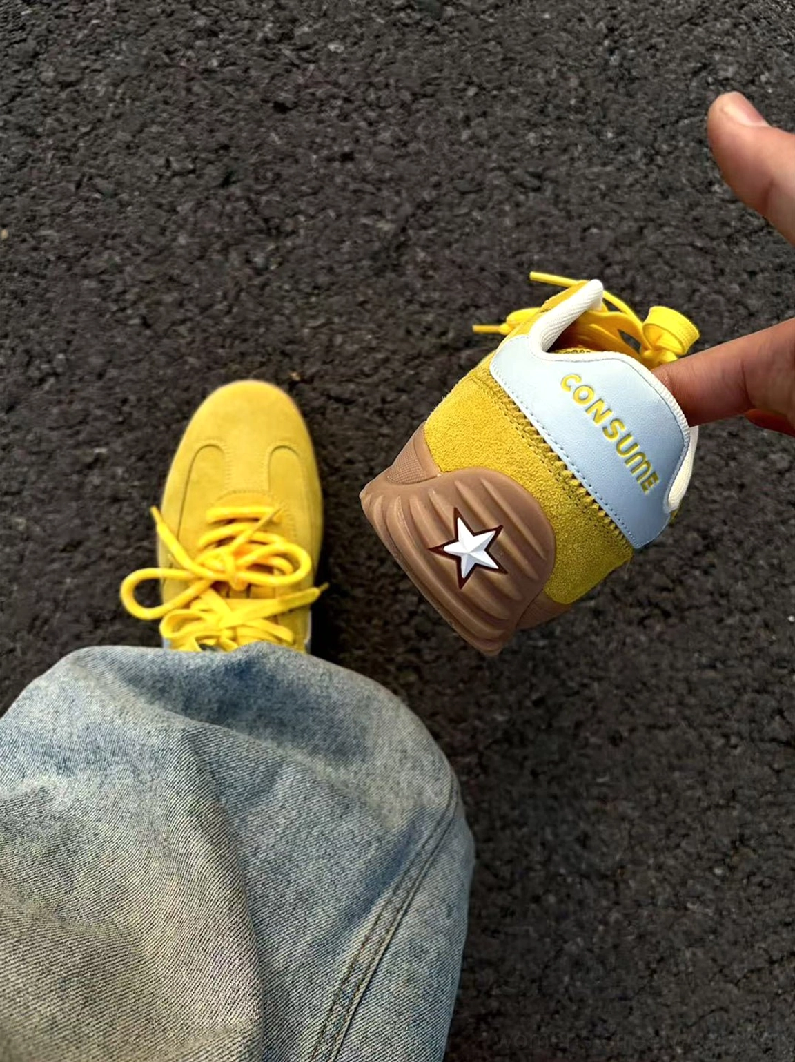 Close-up of yellow suede star sneakers showing the light blue heel panel, white heel emblem, and printed heel detail