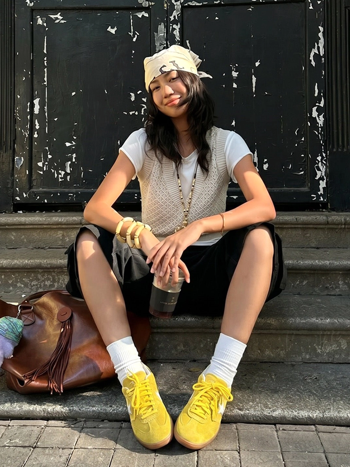 Yellow suede star streetwear trainers worn with white crew socks and a neutral knit vest on a vintage urban stairway