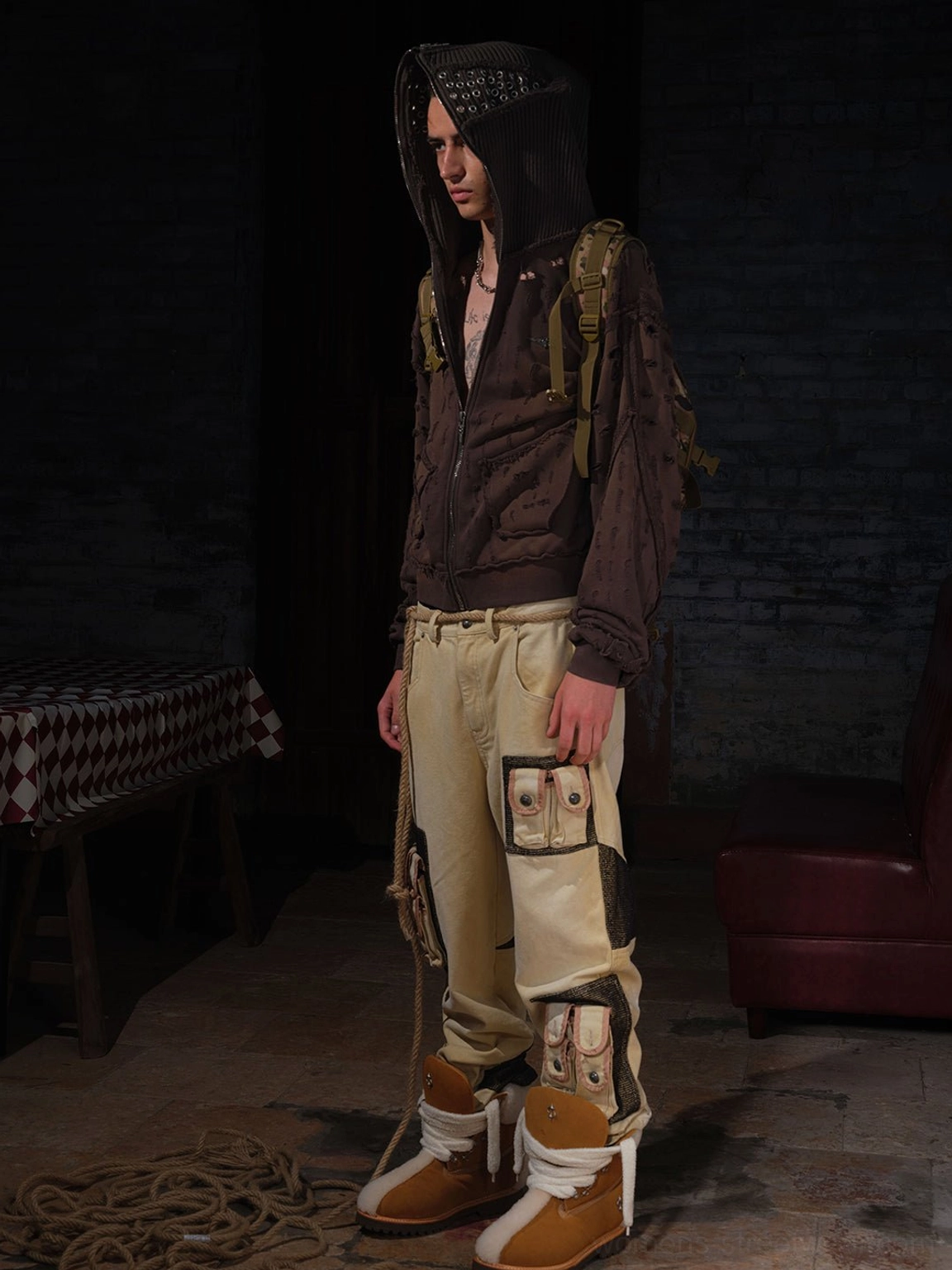 Model wearing yellow tan shearling-lined work boots with utilitarian streetwear clothing in a dark vintage studio, demonstrating the chunky winter workwear silhouette