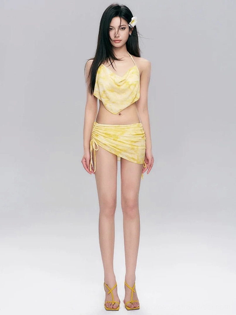 Yellow tie-dye three-piece swim set with triangle halter bikini top, ruched side drawstring skirt, and matte gradient finish