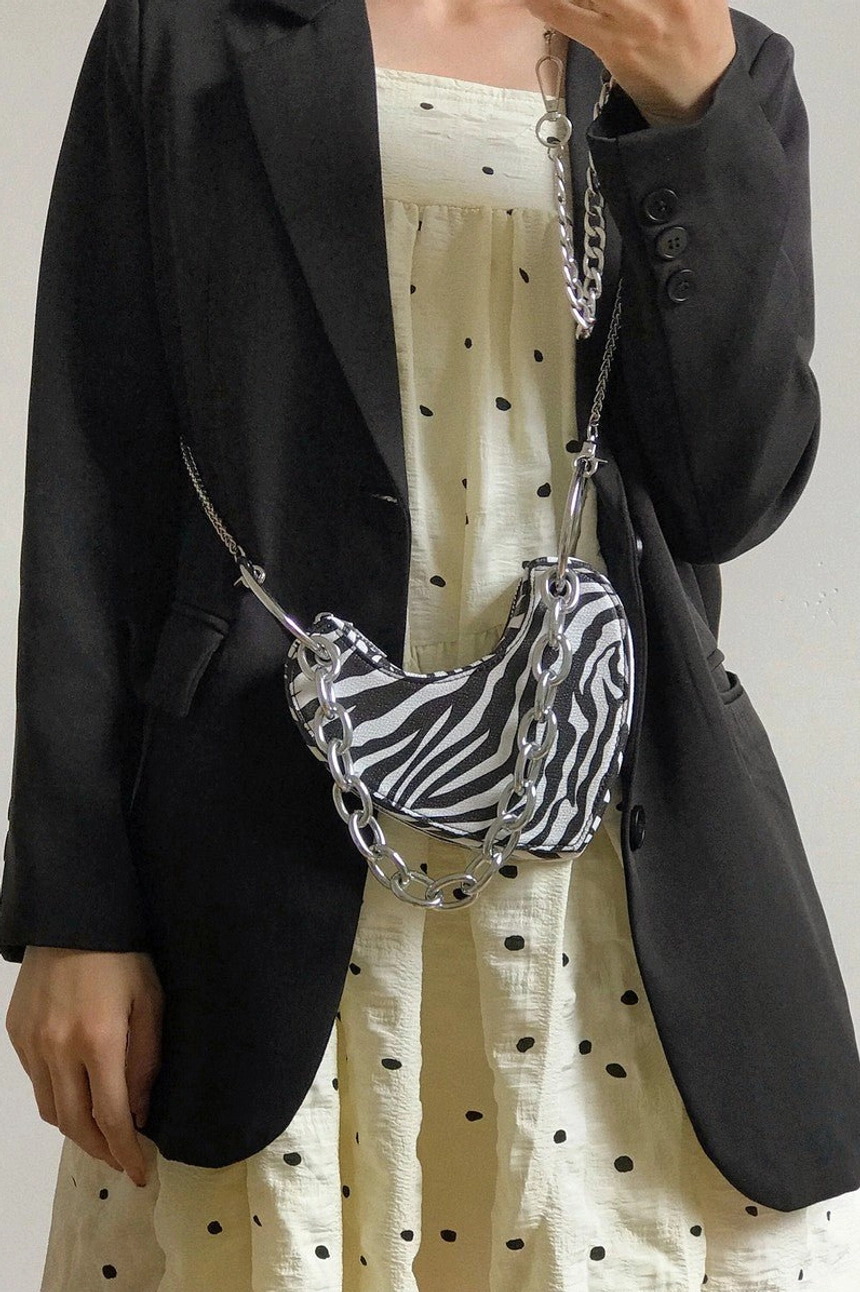 Zebra print heart-shaped chain mini bag worn with black blazer and patterned dress