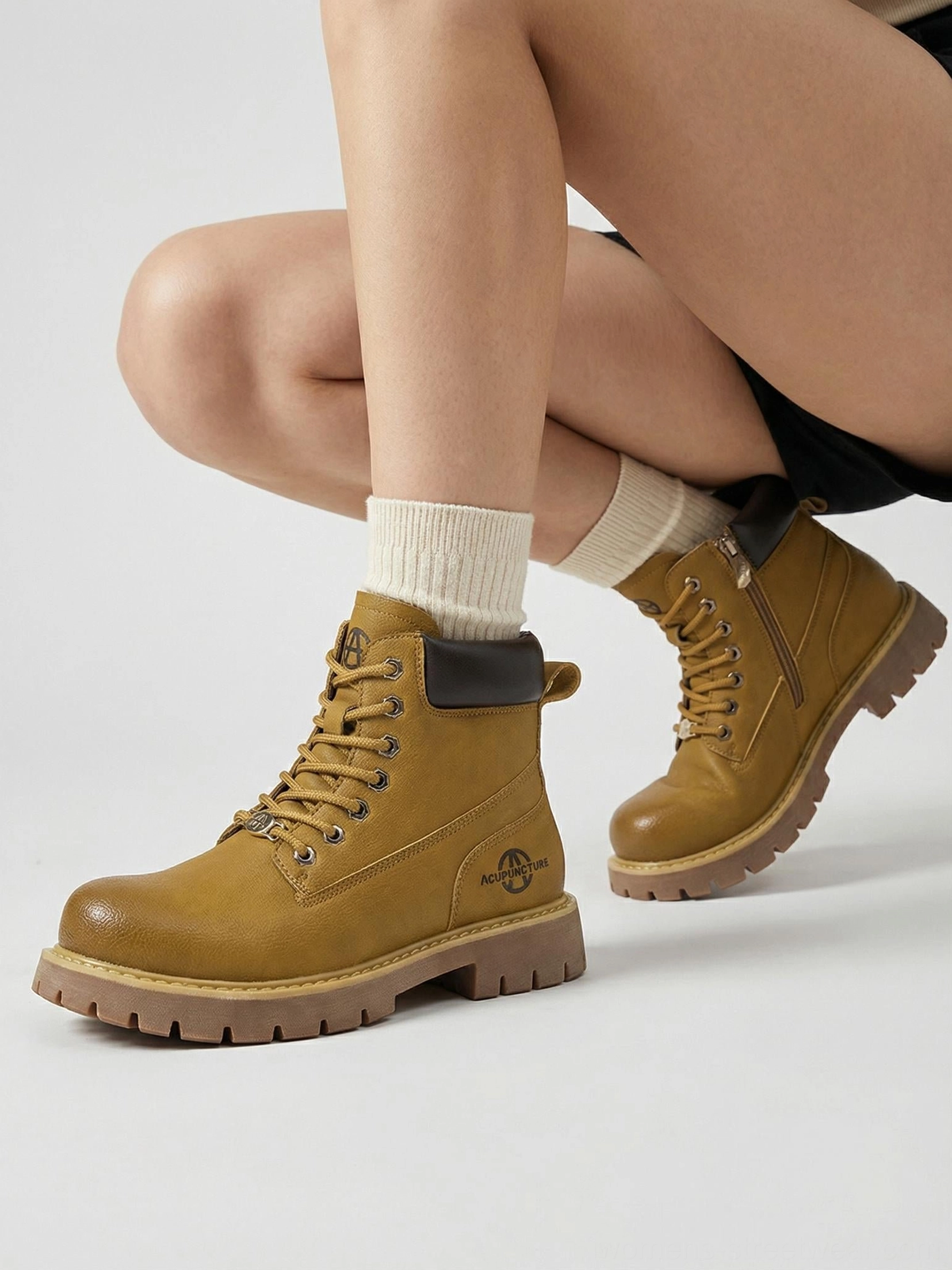 Female wearing tactical zip-front ankle boots white crew socks squatting pose low angle street style photography